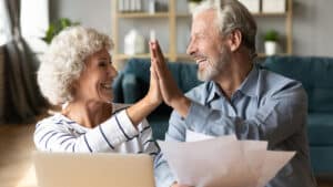 two seniors high fiving while looking at final expense life insurance policy