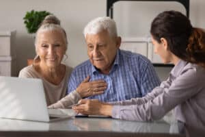 older couple smiling at laptop next to final expense insurance agent